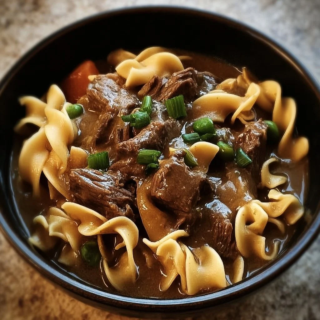 Slow cooker beef and noodles served in a bowl with herbs and spices.